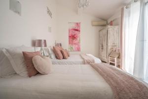 a white bedroom with two beds with pink pillows at Hôtel Le Méditerranée in Hyères