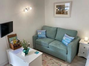 a living room with a green couch and a coffee table at Sweet Caroline - luxury studio stone’s throw from Mousehole harbour in Mousehole