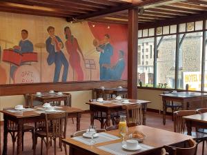 un ristorante con tavoli in legno e un dipinto sul muro di Hotel de Normandie a Saint-Aubin-sur-Mer