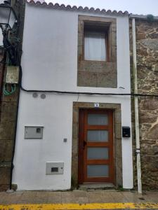 a building with a brown door and a window at Casa Xenoveva in Fisterra