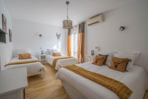two beds in a room with white walls and wooden floors at Hôtel Le Méditerranée in Hyères