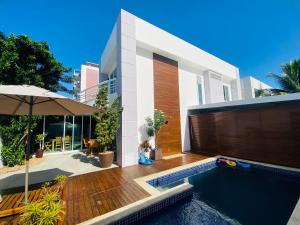 a house with a swimming pool and an umbrella at Cabo Frio Familiar Toca de Gente Feliz in Cabo Frio