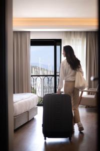 una mujer parada en una habitación de hotel con una maleta en La Farine Hotel en Fethiye