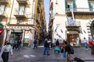 un gruppo di persone che camminano per una strada con edifici di Suites Trinità in Toledo street a Napoli