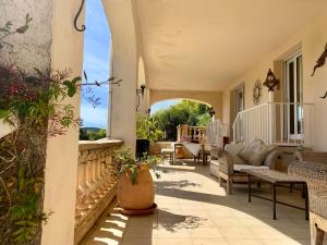 patio al aire libre con mesa, sillas y porche en Villa des Sapins en Peymeinade