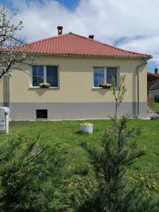 een huis met twee ramen en een groene tuin bij Livi Apartman in Szentantalfa