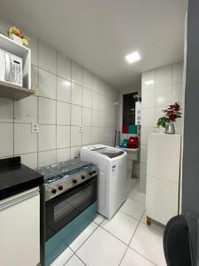 a small kitchen with a stove and a refrigerator at Apartamento Condominio Emilio Hinko - Beira Mar in Fortaleza