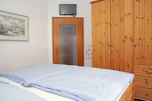 クックスハーフェンにあるFischerhus _ Wohnung 3のベッドルーム1室(ベッド1台付)、木製キャビネットが備わります。