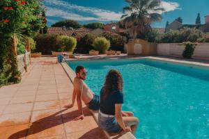 un hombre y una mujer sentados junto a una piscina en Résidence l'Oustal des Mers, en Gruissan