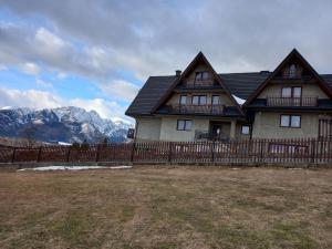 a house with a fence and mountains in the background at Niebiańska Grań in Zakopane