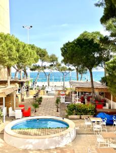 uma piscina com mesas e cadeiras e a praia em Hotel Venteo em Platja d'Aro