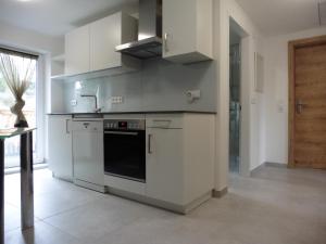a kitchen with white cabinets and a stove top oven at Moerth Apartment in Schalchham