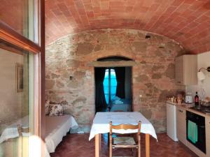 a kitchen with a table in a room with a brick wall at Podere Alberello in Torrita di Siena