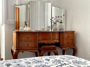 a dressing table with a mirror and flowers on it at Casa Às Sete in Angra do Heroísmo