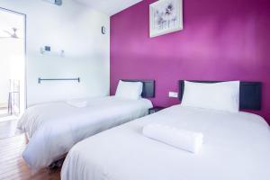 2 Betten in einem Zimmer mit lila Wänden in der Unterkunft Explore 4BR Gardenhouse Retreats (Free Parking) in Butterworth