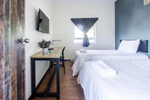Zimmer mit 2 Betten, einem Tisch und einem Fenster in der Unterkunft Explore 4BR Gardenhouse Retreats (Free Parking) in Butterworth