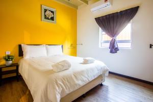 a bedroom with a large bed with a yellow wall at Explore 4BR Gardenhouse Retreats (Free Parking) in Butterworth