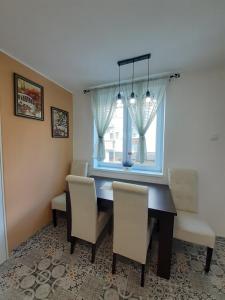 comedor con mesa, sillas y ventana en Apartman Jovana en Sremska Mitrovica