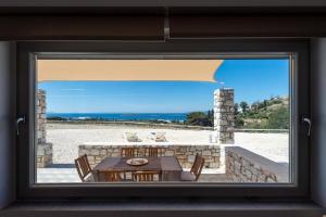 Z okna roztacza się widok na patio ze stołem i krzesłami. w obiekcie Panteronisia View Villa w mieście Angairiá