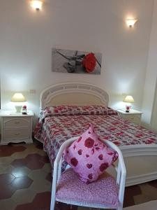 a bedroom with a bed with a pink pillow and two tables at Appartamento vacanze Le rose in Bosa