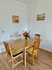 un tavolo in legno con sedie e un vaso di fiori sopra di Gartenapartment Storchenblick a Weiden am See