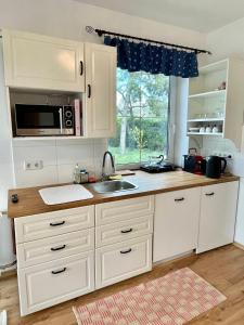 a kitchen with white cabinets and a sink and a window at Gartenapartment Storchenblick in Weiden am See