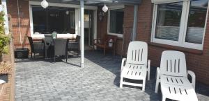 two white chairs and a table on a patio at Ferienwohnung Nordseetraum in Hage