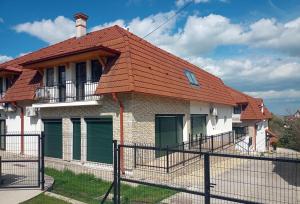 una casa con tetto rosso e recinzione di Szellőrózsa Apartman a Fonyód
