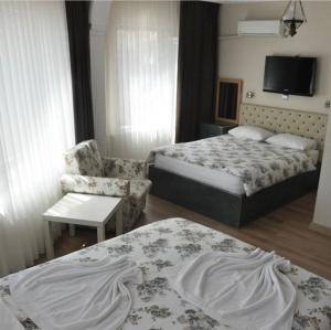 a hotel room with two beds and a chair at Choo Choo Pansiyon in Isparta