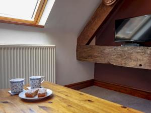 een houten tafel met twee kopjes en twee gebakjes erop bij Pass the Keys Quaint 1 bedroom cottage in Church Stretton in Church Stretton