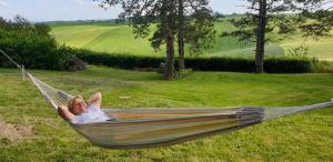 a woman laying in a hammock in a field at CHAMBRE D'HOTE 40 M2 très agréable 