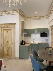 a kitchen with green cabinets and a table with chairs at Chambre Familiale Maison de L'Église du Couvent in Narbonne