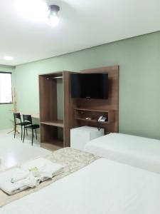 a bedroom with two beds and a flat screen tv at Hotel Cantinho Verde in Teixeira de Freitas