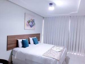 a bedroom with a large white bed with blue pillows at Hotel Cantinho Verde in Teixeira de Freitas