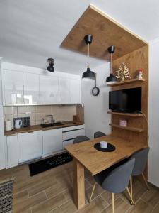 a kitchen with white cabinets and a wooden table at Kai Apartman in Kopaonik