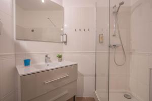 a white bathroom with a sink and a shower at Hôtel Le Méditerranée in Hyères