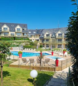 a swimming pool with chairs and a resort at Appart Omaha Beach in Port-en-Bessin-Huppain