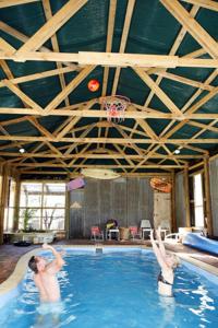 two people in a swimming pool with a basketball hoop at Lovedale Cottages Hunter Valley in Lovedale