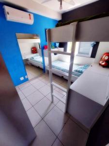 um pequeno quarto com 2 beliches e uma parede azul em Praia da Enseada, com lazer total. no Guarujá