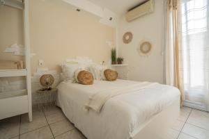 a white bedroom with a large white bed with pillows at Hôtel Le Méditerranée in Hyères