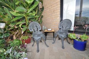 two chairs and a table on a patio with plants at Beachfront Apartments in Narooma