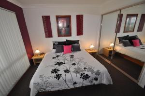 een slaapkamer met een bed met een zwart-witte deken bij Beachfront Apartments in Narooma