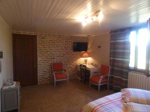 a room with a bed and two chairs and a desk at La mare aux grenouilles in Bruailles