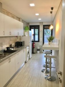 uma cozinha com armários brancos e uma mesa e cadeiras em Alojamento Amélie - Apartamento em Braga