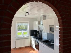 a kitchen with white cabinets and a window at Ferienhaus Antje Greetsiel Nordsee in Krummhörn