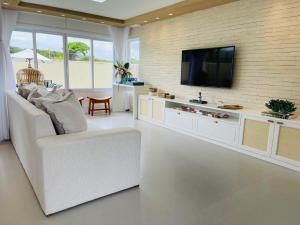 sala de estar con sofá blanco y TV de pantalla plana en Private House Buzios - casa aluguel, en Búzios