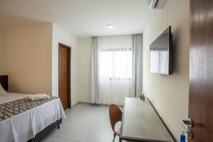 サン・ミゲル・ド・ゴストーゾにあるPousada Terra do Ventoのベッド、テーブル、窓が備わる客室です。