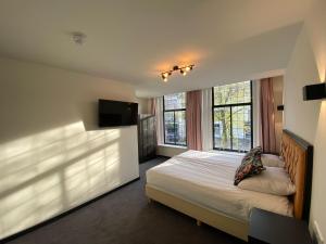 a bedroom with a bed and a flat screen tv at Hotel Bridges House Delft in Delft