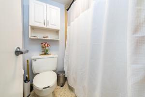 La salle de bains est pourvue d'un rideau de douche blanc et de toilettes. dans l'établissement Wine-y Beach 7th Floor Ocean View King Bed, à Daytona Beach Shores
