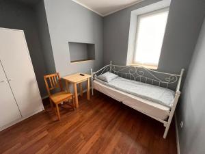a bedroom with a bed and a chair and a window at Hostel WOKU in Świebodzice